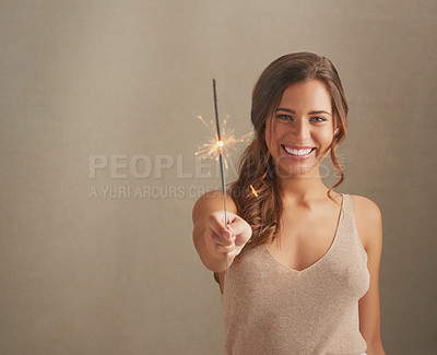 Buy stock photo Studio shot of a beautiful young woman holding sparklers against a brown background