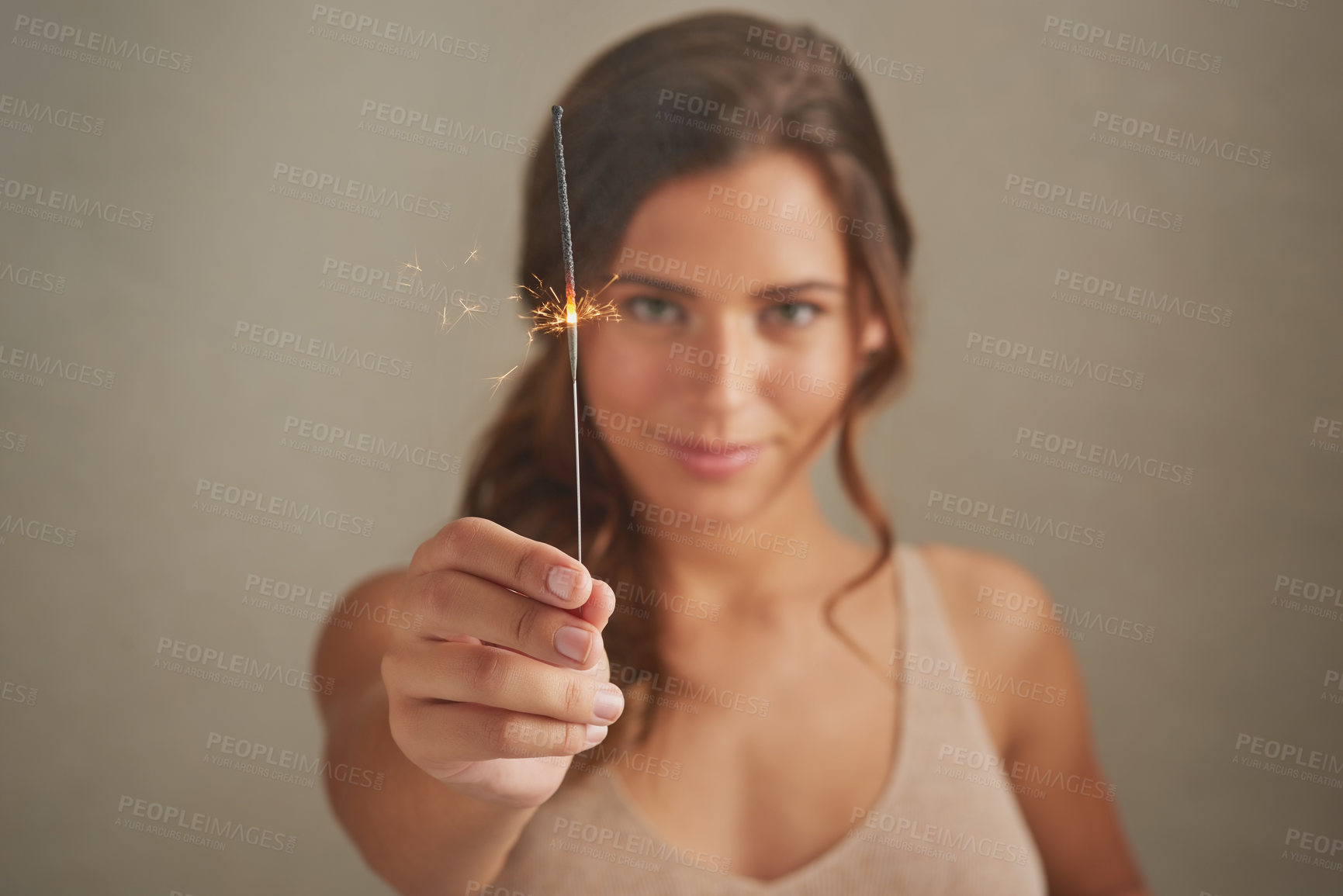 Buy stock photo Studio shot of a beautiful young woman holding sparklers against a brown background