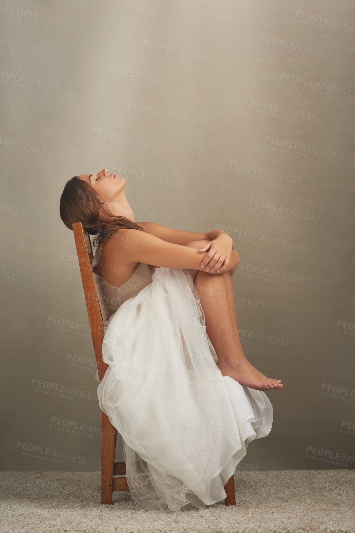 Buy stock photo Studio shot of an attractive young woman looking depressed while sitting on a chair
