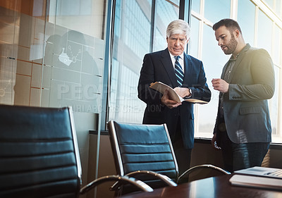 Buy stock photo Cropped shot of two businessmen looking over some paperwork in the office