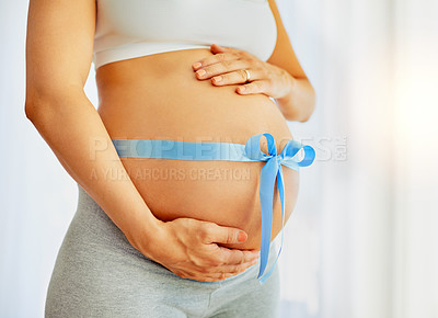 Buy stock photo Cropped shot of a pregnant woman with a blue ribbon tied around her belly