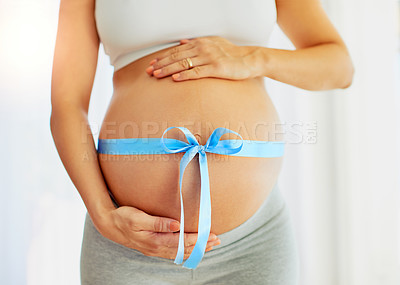 Buy stock photo Cropped shot of a pregnant woman with a blue ribbon tied around her belly