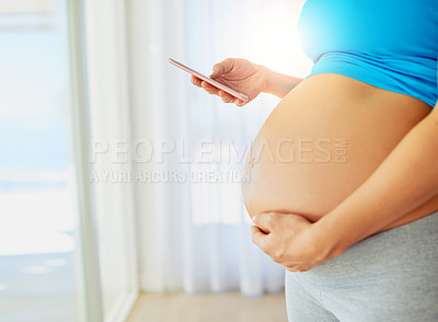Buy stock photo Cropped shot of a pregnant woman using a mobile phone at home