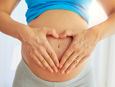 Buy stock photo Cropped shot of a pregnant woman making a heart gesture with her hands around her belly