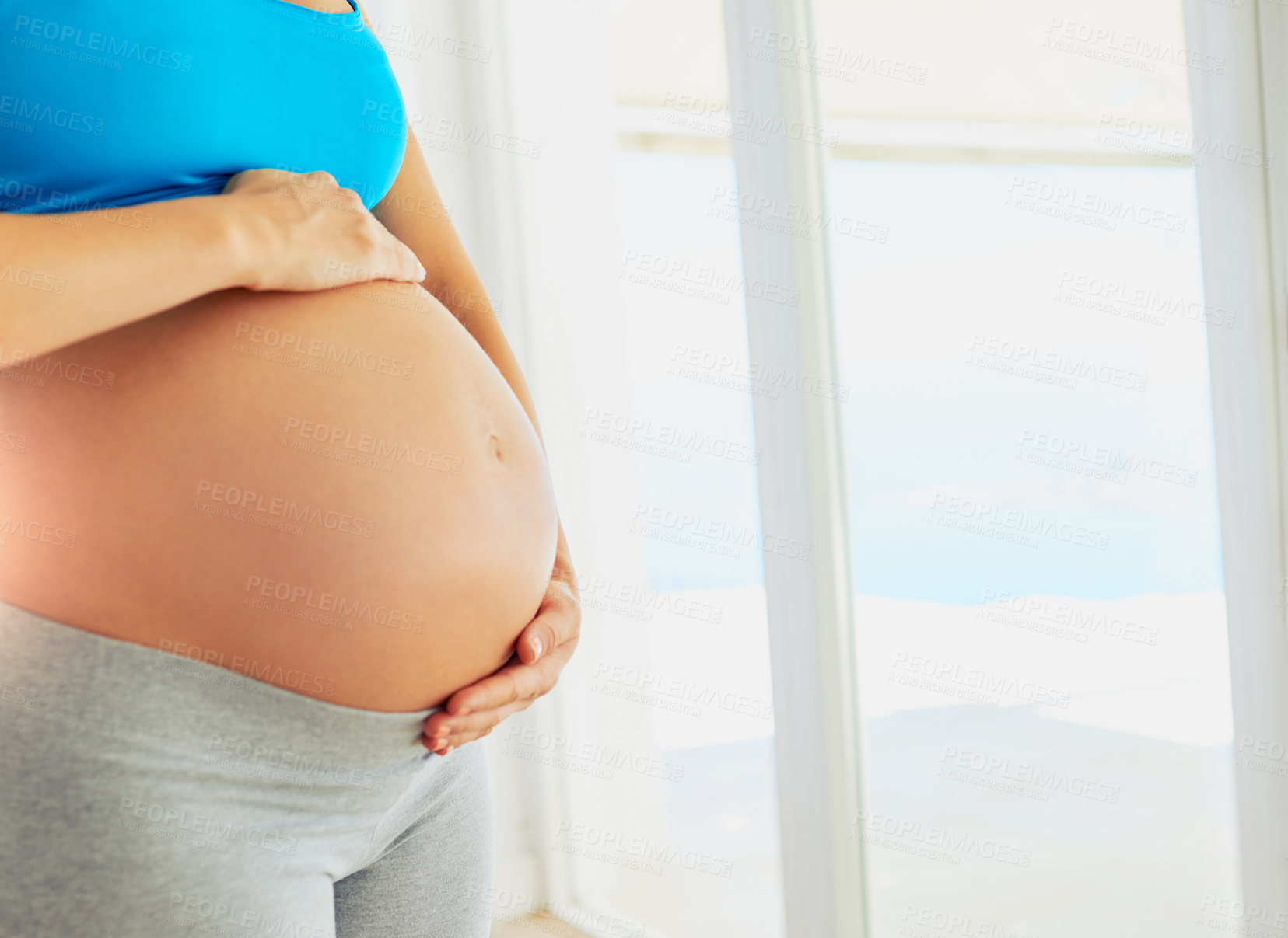 Buy stock photo Pregnant, home and hands of woman by window for comforting, bonding and support in morning. Maternity love, pregnancy and person holding stomach for motherhood, fertility health and baby wellness