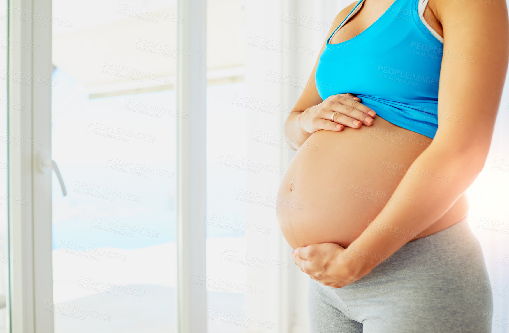 Buy stock photo Cropped shot of a pregnant woman holding her bare belly at home