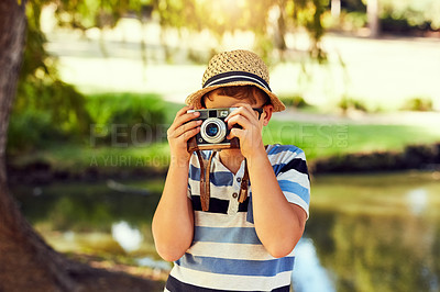 Buy stock photo Shot of a little boy taking a photo with a vintage camera at the park