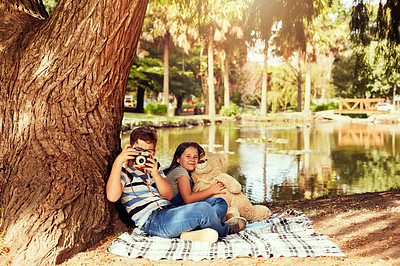 Buy stock photo Portrait of two little siblings having fun while sitting on a blanket at the park
