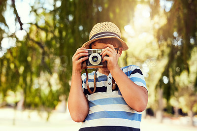 Buy stock photo Shot of a little boy taking a photo with a vintage camera at the park