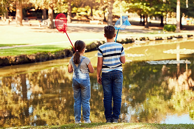 Buy stock photo Rear view shot of two young siblings holding fishing nets at a lake in the park