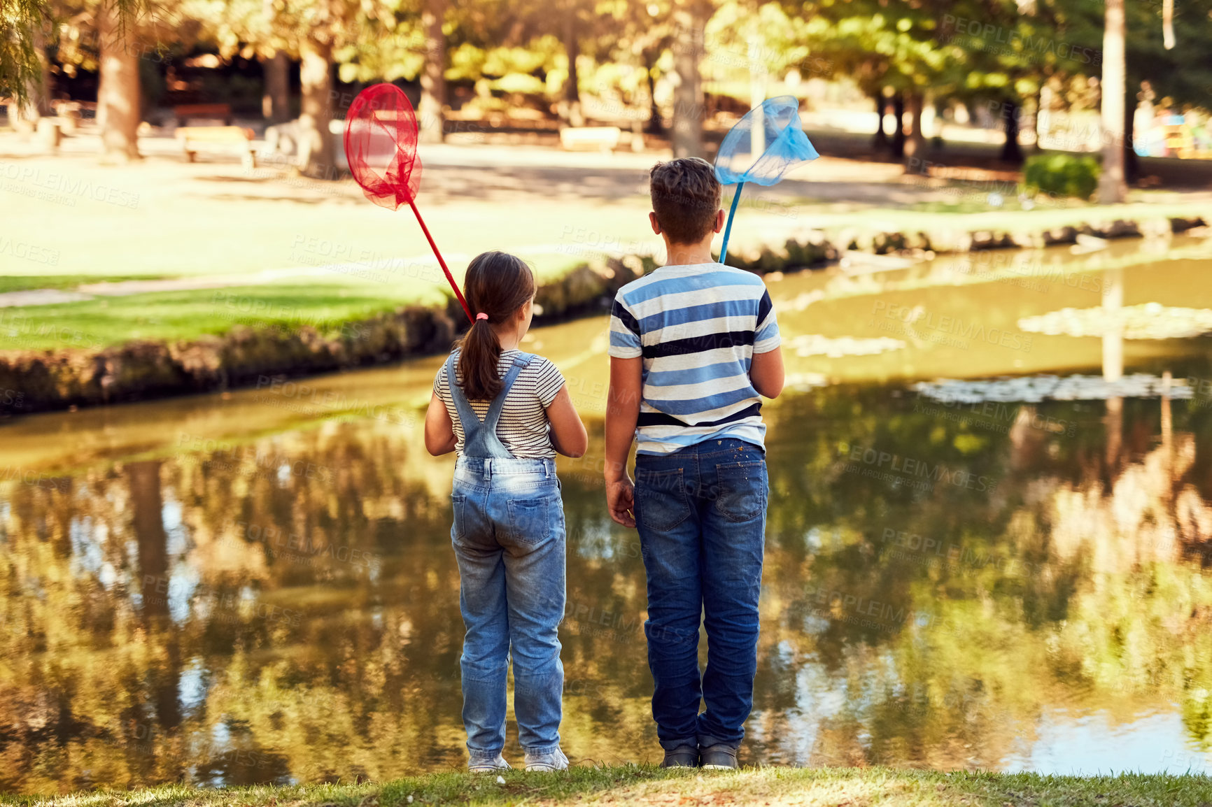 Buy stock photo Rear view shot of two young siblings holding fishing nets at a lake in the park