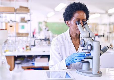 Buy stock photo Shot of a female scientist using a microscope in a lab