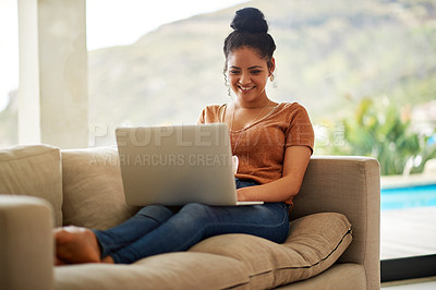 Buy stock photo Shot of a beautiful young woman sitting on a sofa using a laptop at home