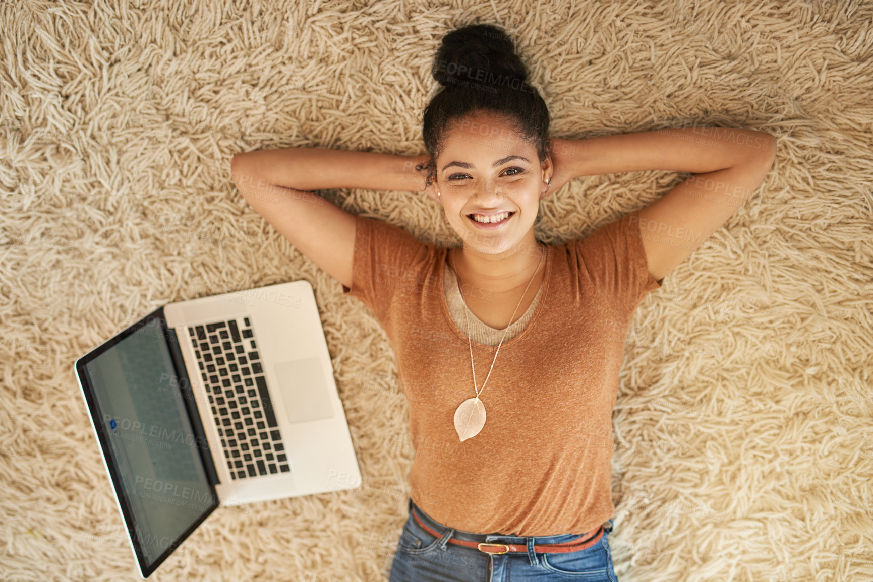 Buy stock photo Shot of a beautiful young woman lying down next to a laptop at home