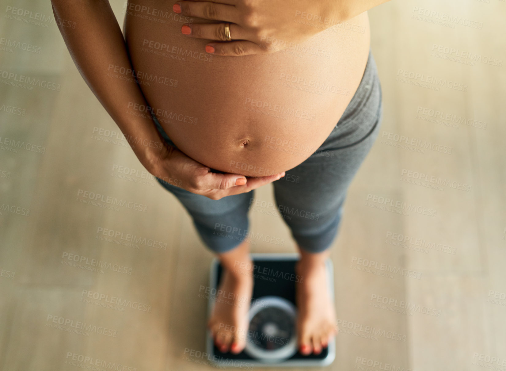 Buy stock photo Cropped high angle shot of a pregnant woman weighing herself on a scale