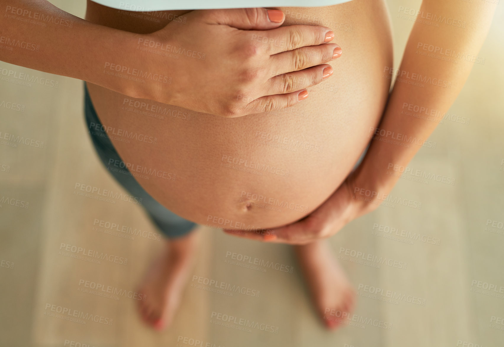 Buy stock photo Cropped high angle shot of a pregnant woman holding her bare belly