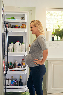 Buy stock photo Shot of a pregnant woman looking inside the fridge at home