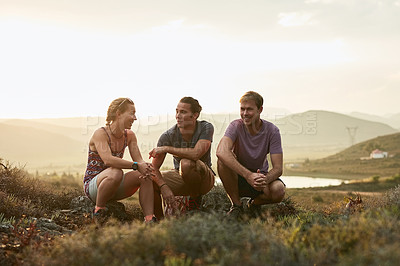 Buy stock photo Shot of three happy young hikers taking a break on a mountain trail