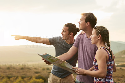 Buy stock photo Shot of three young hikers consulting a map while exploring a new trail