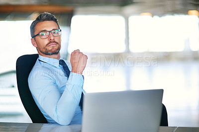 Buy stock photo Shot of a confident businessman sitting behind his laptop in the office