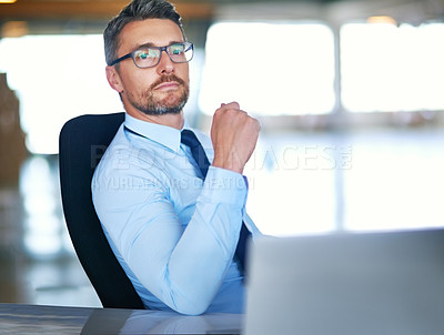 Buy stock photo Shot of a confident businessman sitting behind his laptop in the office