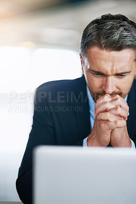 Buy stock photo Shot of a worried businessman looking at his laptop with trepidation in the office