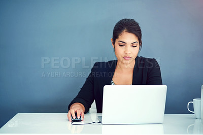 Buy stock photo Shot of a focussed young businesswoman working behind her laptop in the office
