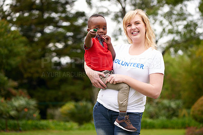 Buy stock photo Shot of a female volunteer carrying a little boy