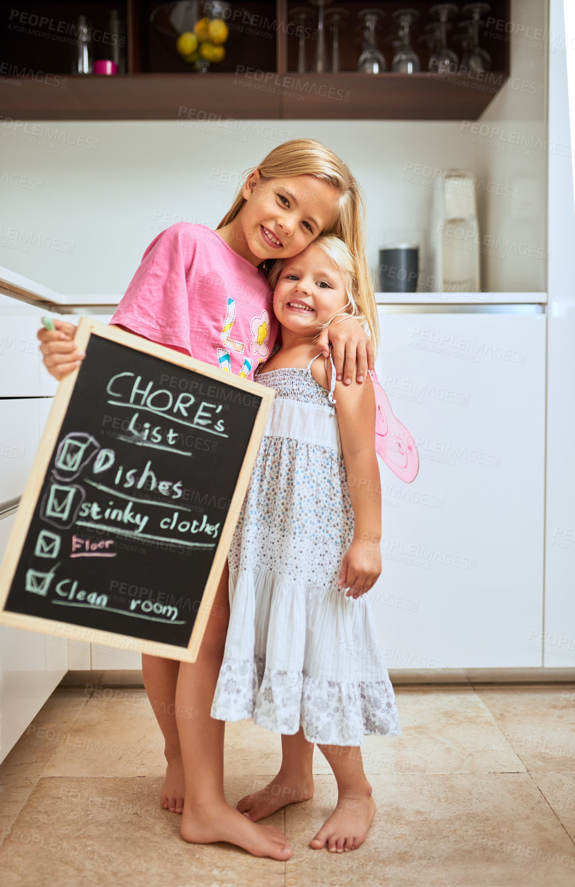 Buy stock photo Portrait of two little girl holding a chalkboard with a completed list of chores at home