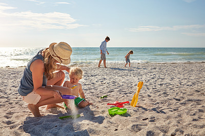 Buy stock photo Shot of a young family enjoying a summer day out at the beach