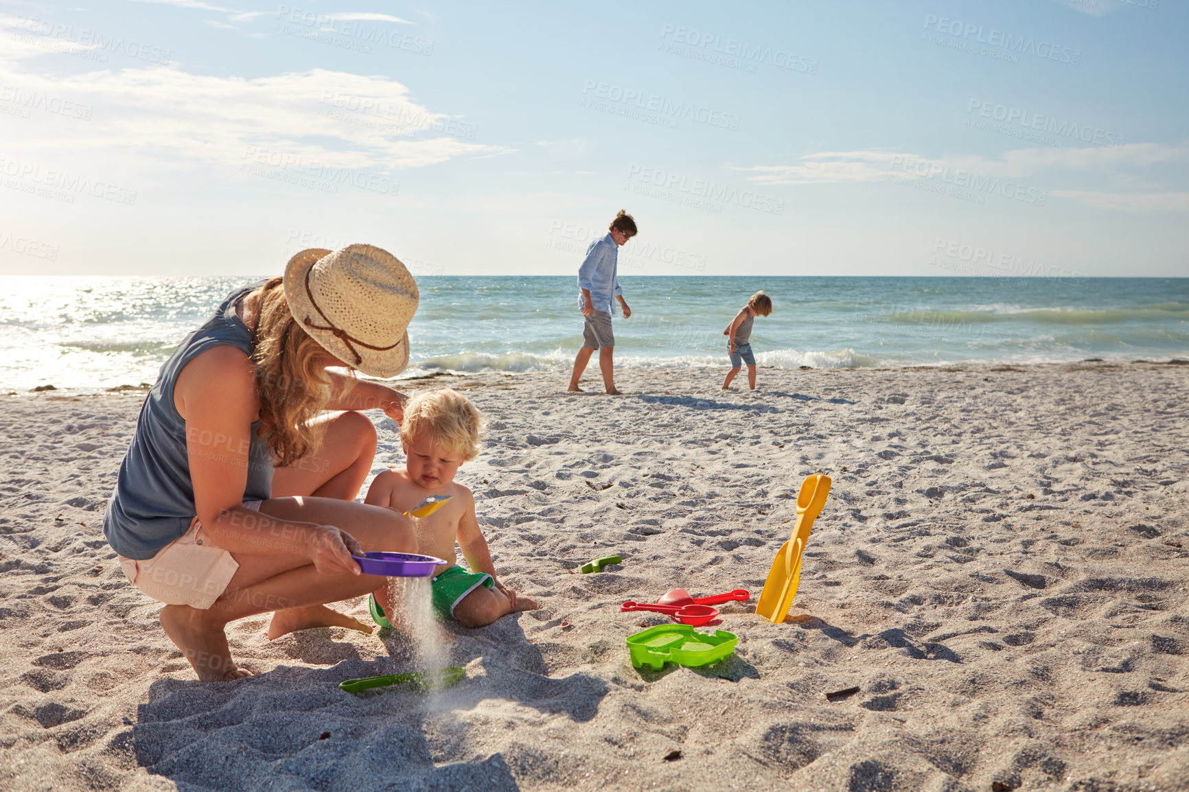 Buy stock photo Shot of a young family enjoying a summer day out at the beach