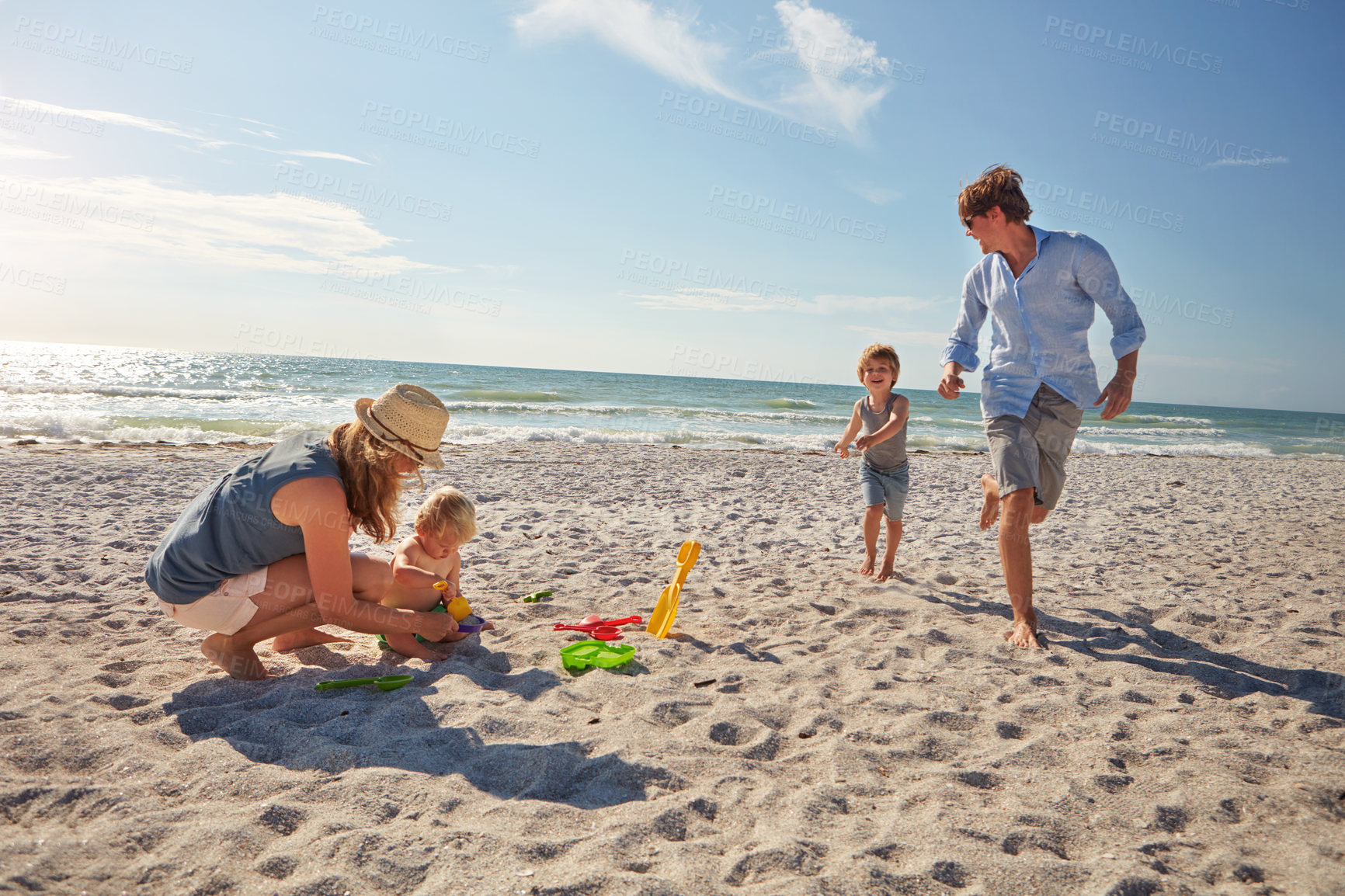 Buy stock photo Toys, sand and love with family at beach for summer vacation, bonding and playing. Support, game and sandcastle with parents and children outdoor for tropical holiday, travel and digging together