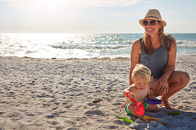 Buy stock photo Shot of a young woman and her son enjoying a summer day out at the beach