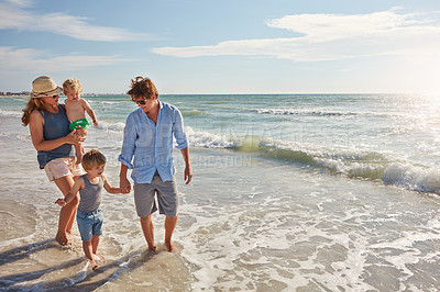 Buy stock photo Shot of a young family enjoying a summer day out at the beach