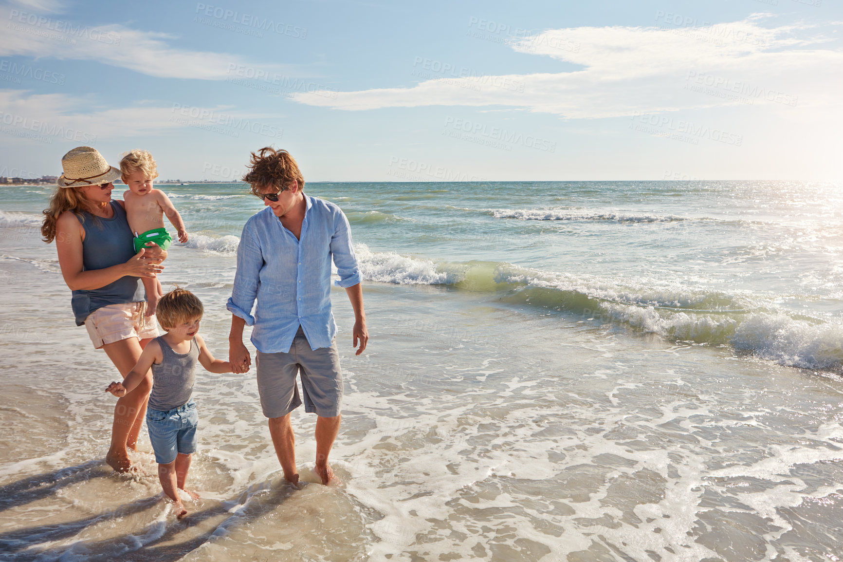 Buy stock photo Shot of a young family enjoying a summer day out at the beach