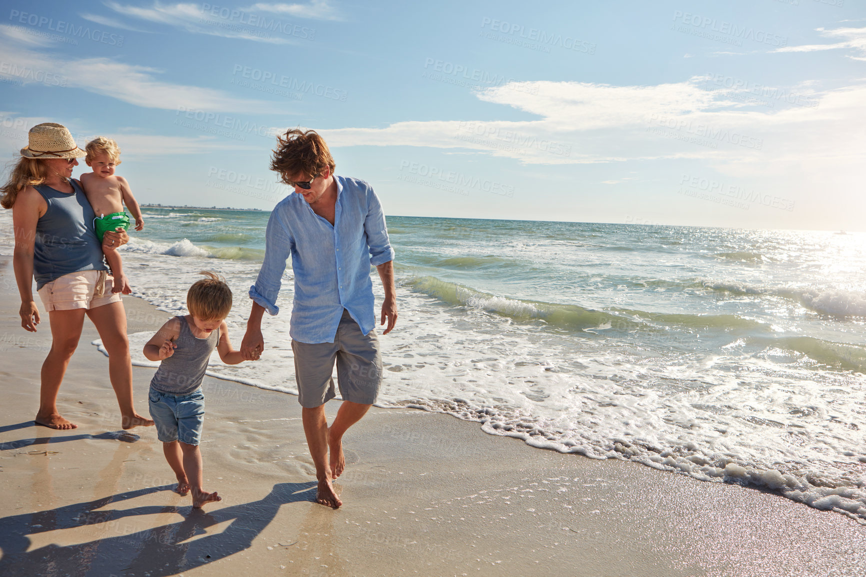 Buy stock photo Shot of a young family enjoying a summer day out at the beach