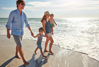 Buy stock photo Shot of a young family enjoying a summer day out at the beach