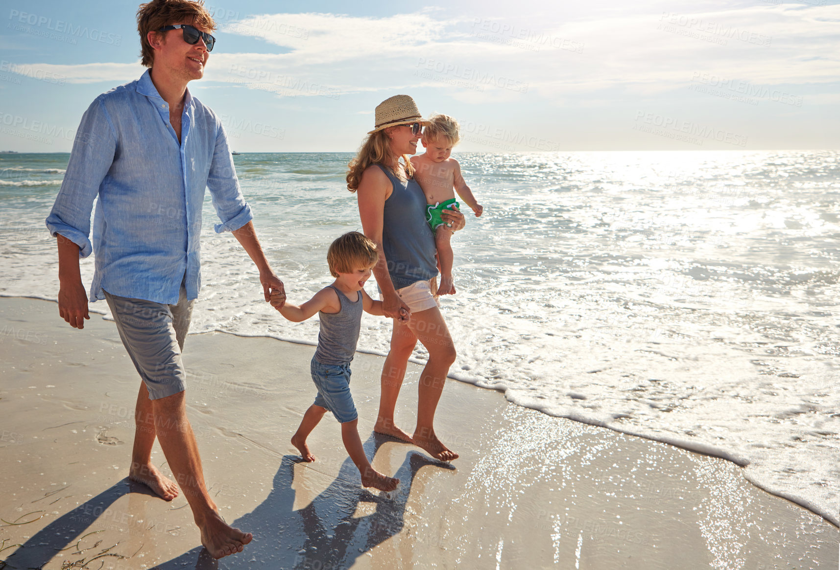 Buy stock photo Shot of a young family enjoying a summer day out at the beach