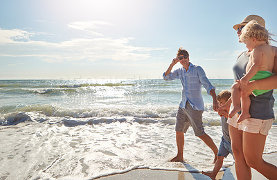 Buy stock photo Shot of a young family enjoying a summer day out at the beach