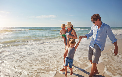 Buy stock photo Shot of a young family enjoying a summer day out at the beach