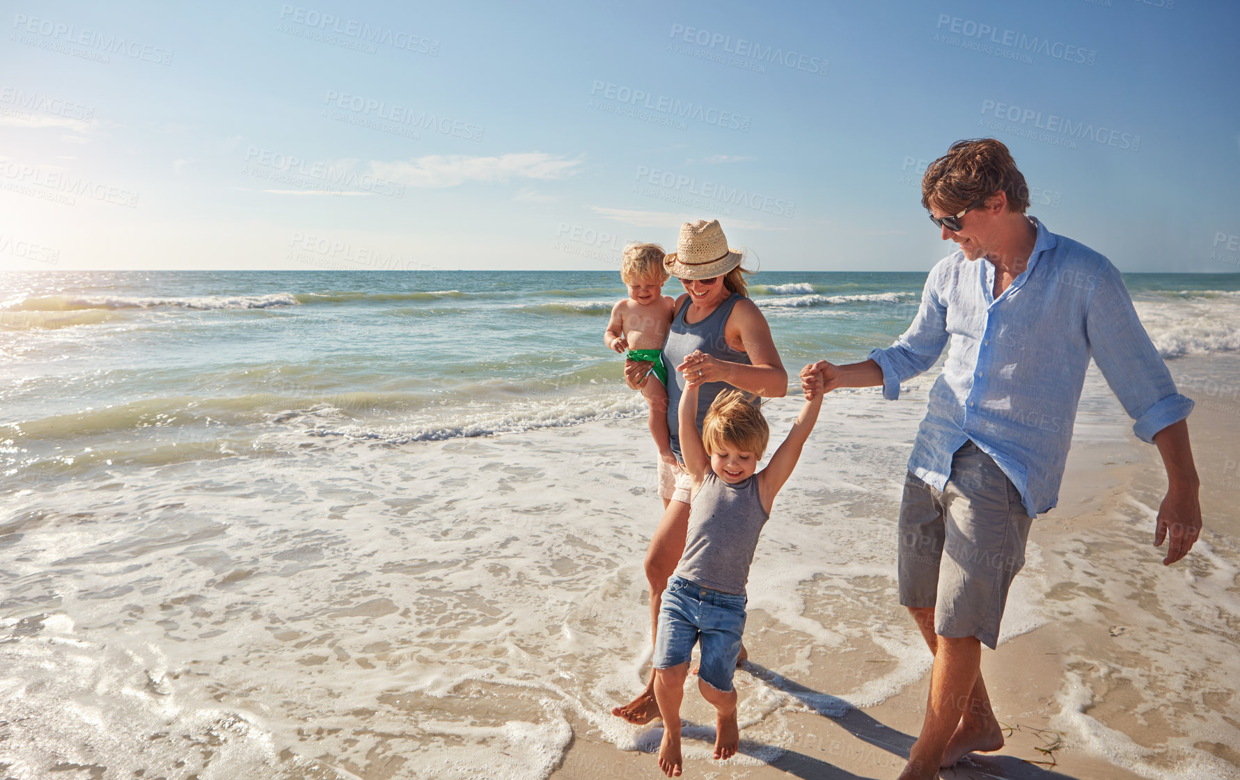 Buy stock photo Shot of a young family enjoying a summer day out at the beach