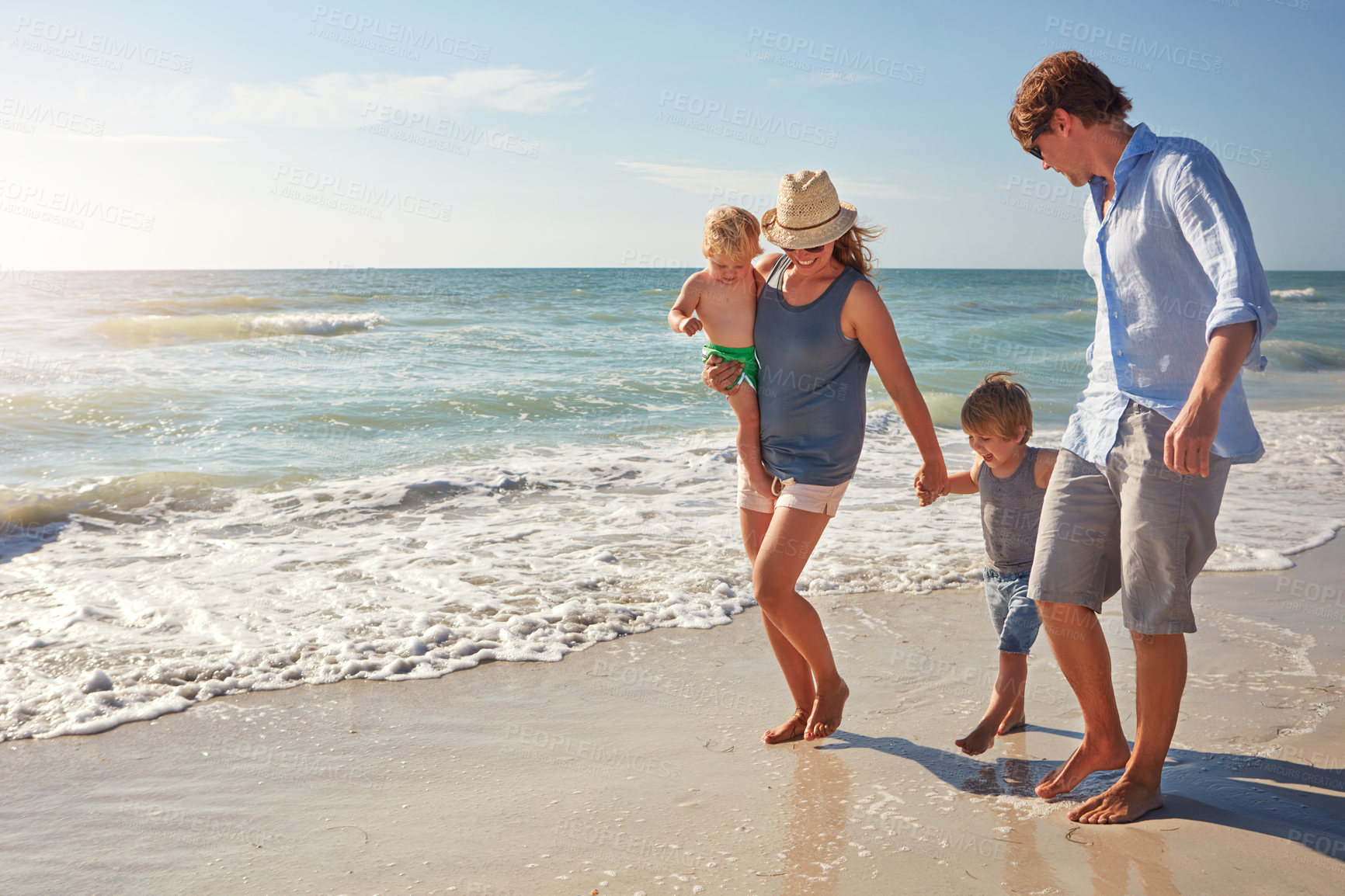 Buy stock photo Shot of a young family enjoying a summer day out at the beach