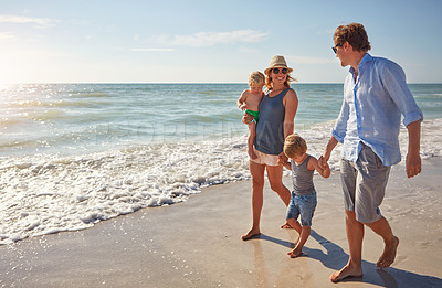 Buy stock photo Shot of a young family enjoying a summer day out at the beach