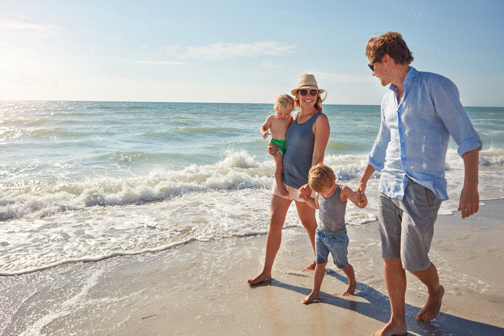 Buy stock photo Shot of a young family enjoying a summer day out at the beach