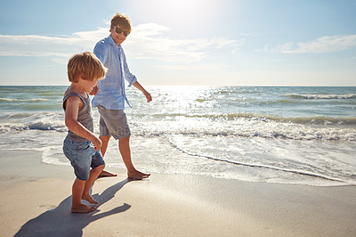 Buy stock photo Shot of a young man and his son enjoying a summer day out at the beach