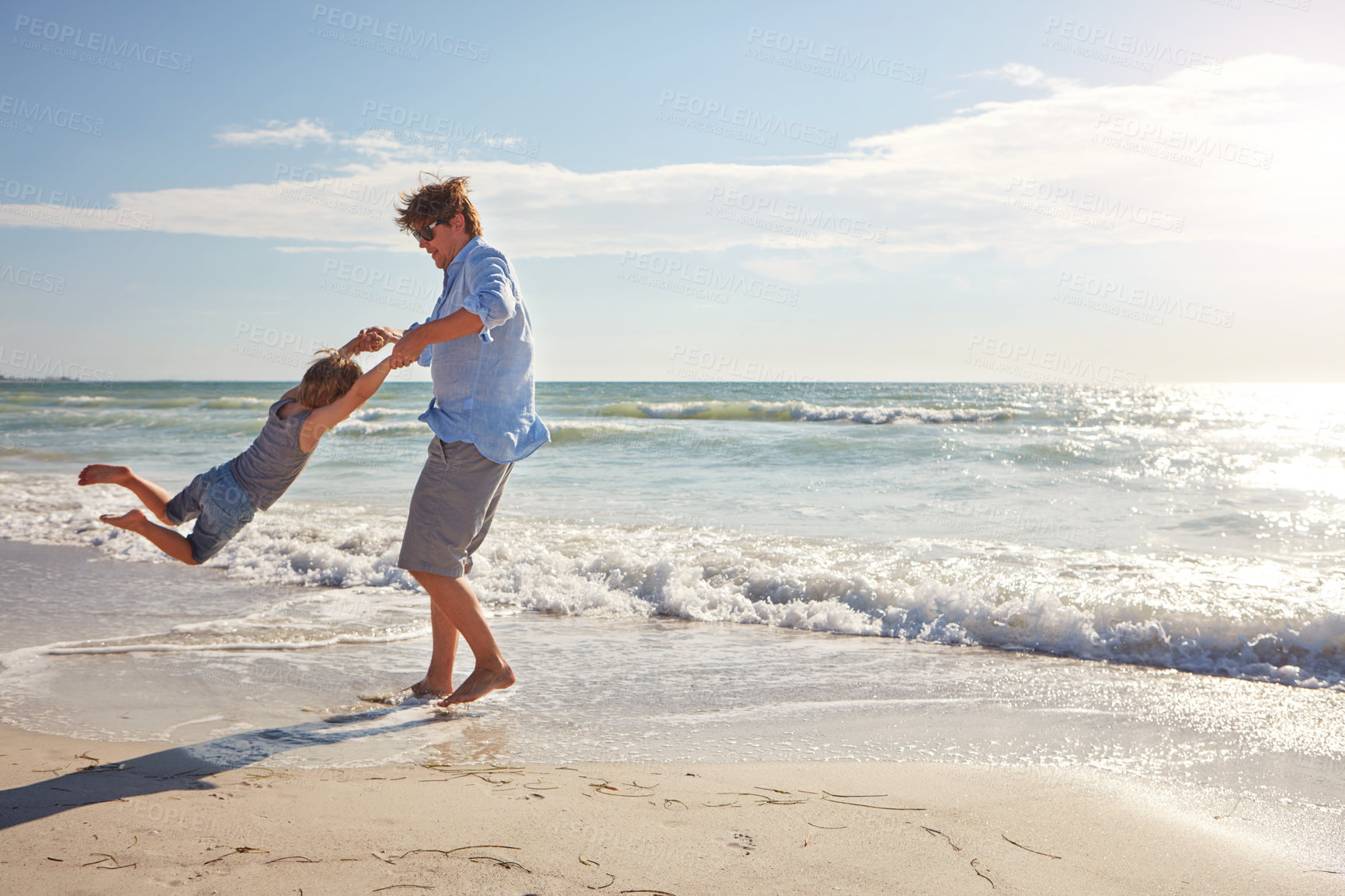 Buy stock photo Shot of a young man and his son enjoying a summer day out at the beach