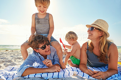 Buy stock photo Playing, piggyback or children with parents at beach on holiday vacation or happy family weekend together. Father, fun mother or kids siblings at sea for bonding or picnic in nature in Spain to relax