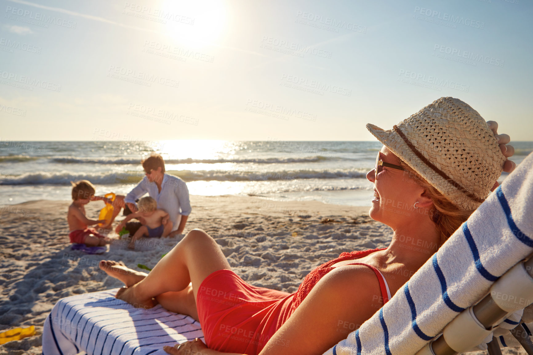 Buy stock photo Chair, sunset or kids with woman at beach on holiday vacation or weekend together with dad or family. Father, calm mother or children siblings at sea for bonding or break in nature in Spain in summer
