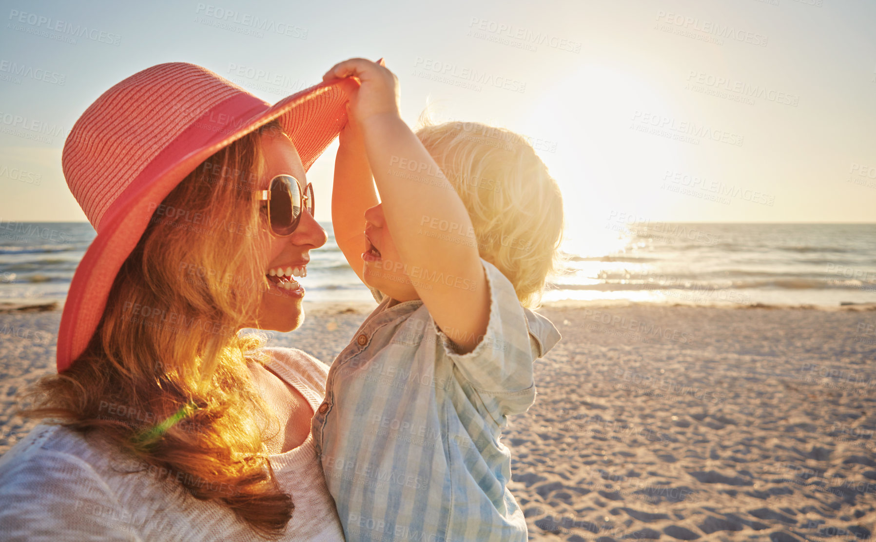 Buy stock photo Happy mother, kid and beach with hug in sunset for outdoor holiday, weekend or bonding in nature. Mom, child and little boy with smile for embrace, love or care in sunshine by ocean coast or sea