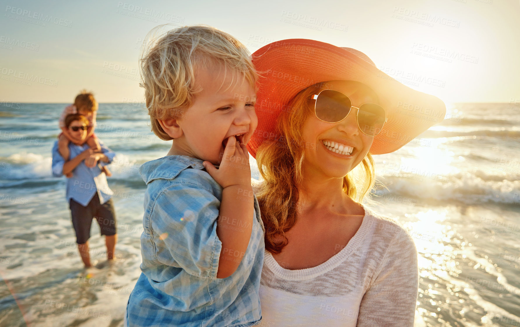 Buy stock photo Happy mother, family and beach with hug in sunset for outdoor holiday, weekend or bonding in nature. Mom, child and little boy with smile for embrace, love or care in sunshine by ocean coast or sea